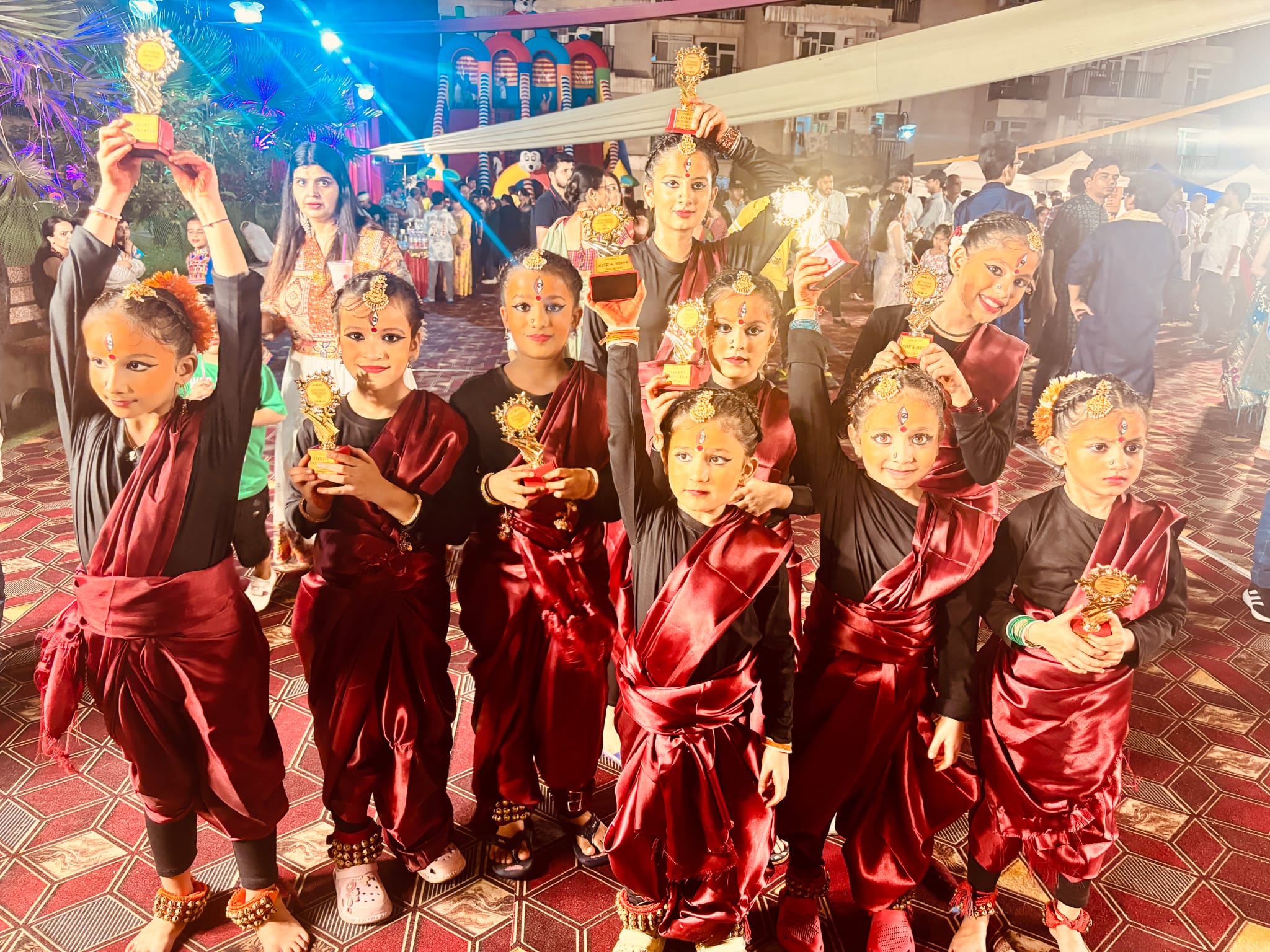 Young dance students holding achievement trophies